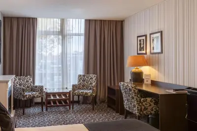 a hotel room with a desk and chairs and a desk at Amsterdam Hotel Uithoorn in Uithoorn