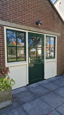 a brick building with a green door and windows at Fenix Edam in Edam