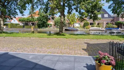 a park with a river and a tree and a flower pot at Fenix Edam in Edam