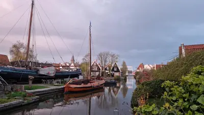 a group of boats docked in a river with houses at Fenix Edam in Edam