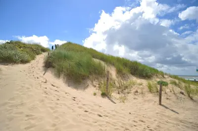 a sandy beach with people walking up a hill at Hotel Zuiderduin in Egmond aan Zee