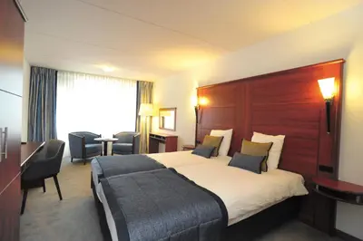 a hotel room with a large bed and a desk at Hotel Zuiderduin in Egmond aan Zee