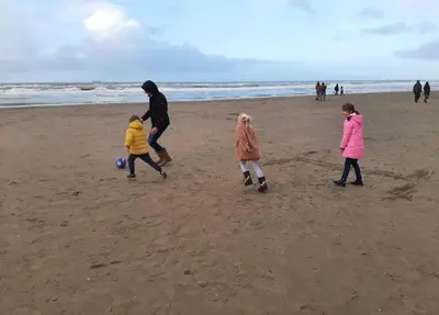 a man and two children playing with a soccer ball on the beach at zomerhuis in Wijk aan Zee! 2 pers in Wijk aan Zee