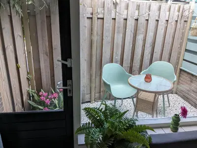a patio with two chairs and a table and a fence at zomerhuis in Wijk aan Zee! 2 pers in Wijk aan Zee