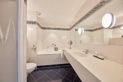 a bathroom with a sink and a tub and a toilet at Carlton Square Hotel in Haarlem