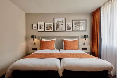 a bedroom with a large bed with orange pillows at Carlton Square Hotel in Haarlem