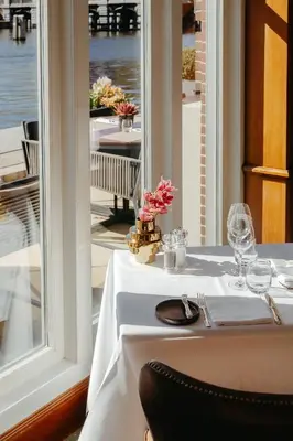 a table with a white table cloth on a table with a window at InterContinental Amstel Amsterdam by IHG in Amsterdam