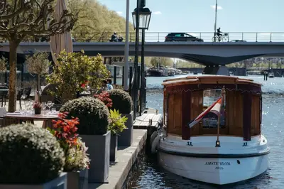 a boat in the water next to a bridge at InterContinental Amstel Amsterdam by IHG in Amsterdam