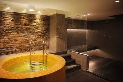 a bathroom with a tub and a stone wall at InterContinental Amstel Amsterdam by IHG in Amsterdam