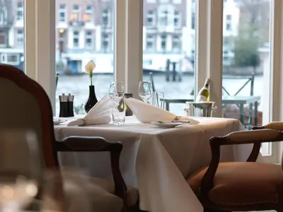 a table with a white table cloth and glasses and a window at InterContinental Amstel Amsterdam by IHG in Amsterdam