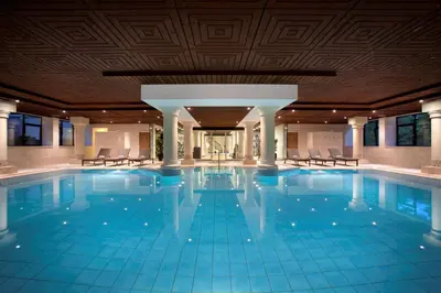 a large swimming pool with chairs in a building at DoubleTree by Hilton Royal Parc Soestduinen in Amersfoort