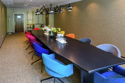 a conference room with a long table and colorful chairs at DoubleTree by Hilton Royal Parc Soestduinen in Amersfoort