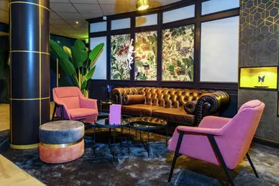 a lobby with a couch and two pink chairs at DoubleTree by Hilton Royal Parc Soestduinen in Amersfoort