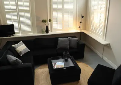 a living room with a black couch and a table at B&B Vechtzicht in Weesp