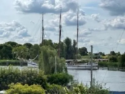 two boats are docked in a river with trees at B&B Vechtzicht in Weesp