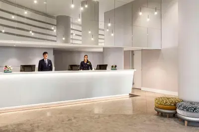 two people standing at a reception desk in a lobby at NH Utrecht in Utrecht