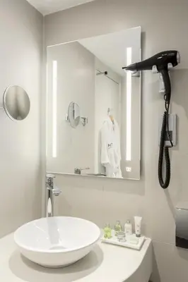 a white bathroom with a sink and a mirror at NH Utrecht in Utrecht
