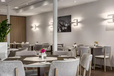a dining room with tables and chairs and lights at NH Utrecht in Utrecht