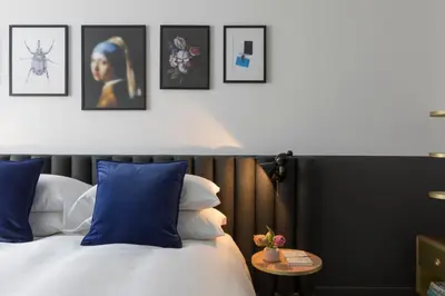 a bedroom with a bed with blue pillows and pictures on the wall at Kimpton De Witt Amsterdam by IHG in Amsterdam
