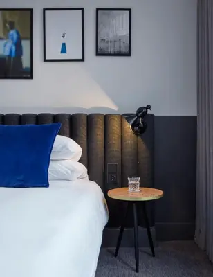 a bedroom with a bed with a blue pillow and a table at Kimpton De Witt Amsterdam by IHG in Amsterdam