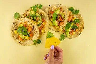 a person is holding a piece of cheese in front of three tacos at Kimpton De Witt Amsterdam by IHG in Amsterdam