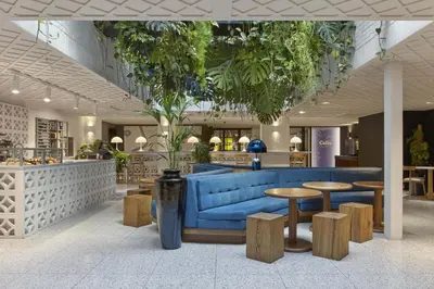 a lobby with a blue couch and tables and plants at Kimpton De Witt Amsterdam by IHG in Amsterdam