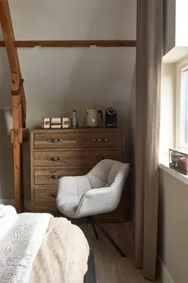 a bedroom with a dresser and a white chair at Brasserie Spoorhuis Mijdrecht in Mijdrecht