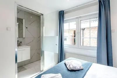 a bedroom with a shower and a bed with blue curtains at Studio Duinzand in Zandvoort