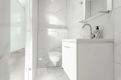 a white bathroom with a toilet and a shower at Studio Duinzand in Zandvoort