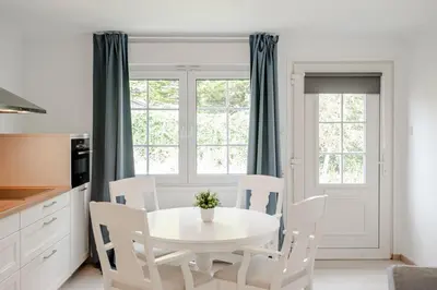 a kitchen with a white table and white chairs at Studio Duinzand in Zandvoort