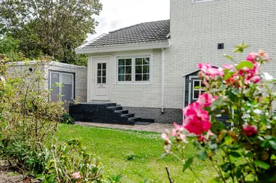 a house with a door and a yard with pink roses at Studio Duinzand in Zandvoort
