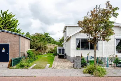 a white house with a driveway and a tree at Studio Duinzand in Zandvoort