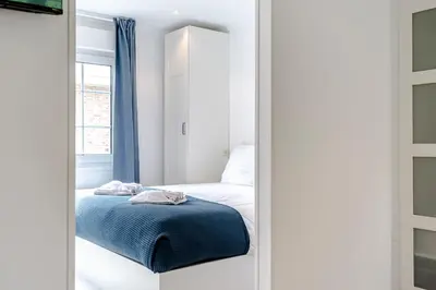 a small bedroom with a bed and a mirror at Studio Duinzand in Zandvoort