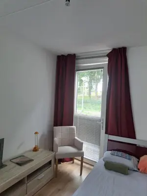 a bedroom with a bed and a chair and a window at Dubbelink 3A in Amsterdam