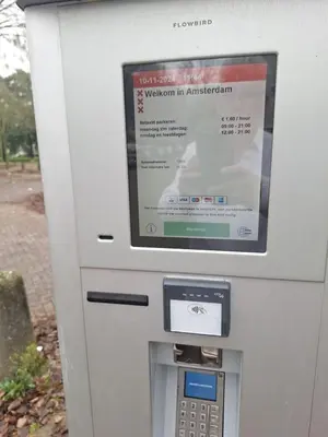 a white parking meter with a sign on it at Dubbelink 3A in Amsterdam