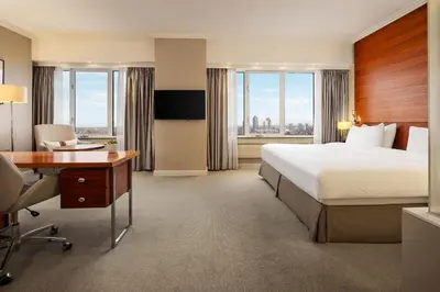 a hotel room with a bed and desk and windows at Hotel Okura Amsterdam – The Leading Hotels of the World in Amsterdam