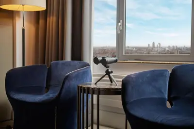 a room with two blue chairs and a table and a window at Hotel Okura Amsterdam – The Leading Hotels of the World in Amsterdam