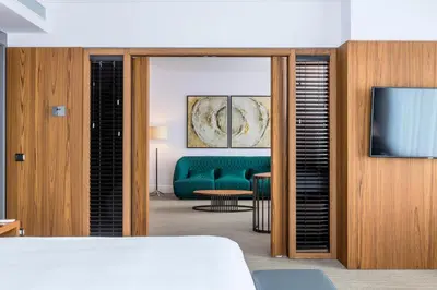 a living room with a green couch and a television at Hotel Okura Amsterdam – The Leading Hotels of the World in Amsterdam