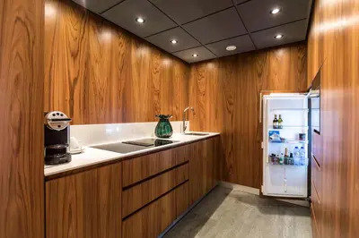 a kitchen with wooden cabinets and a refrigerator at Hotel Okura Amsterdam – The Leading Hotels of the World in Amsterdam