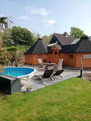 a backyard with a log cabin and a swimming pool at Finse Kota met privé Sauna en Hottub in Spanbroek