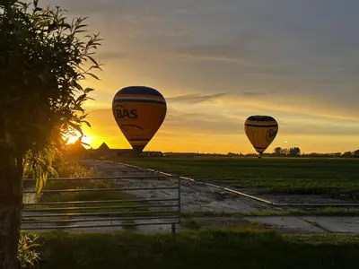 three hot air balloons in a field at sunset at Finse Kota met privé Sauna en Hottub in Spanbroek