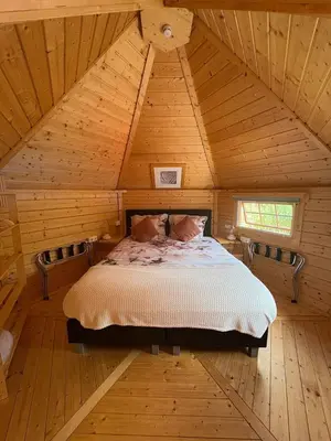 a bedroom with a bed in a wooden attic at Finse Kota met privé Sauna en Hottub in Spanbroek