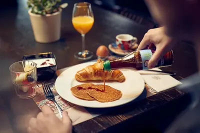 a table with a plate with pancakes and a bottle of wine at WestCord Art Hotel Amsterdam 3 stars in Amsterdam