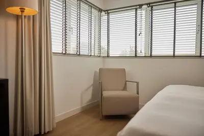 a bedroom with a bed and a chair and windows at WestCord Art Hotel Amsterdam 3 stars in Amsterdam