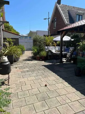 a backyard with a brick patio with a house at De Bollenschuur in Egmond aan Zee