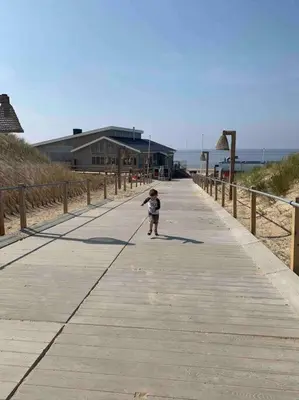 a small child walking down a boardwalk at the beach at De Bollenschuur in Egmond aan Zee