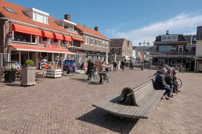 a group of people sitting on a bench in a street at De Bollenschuur in Egmond aan Zee
