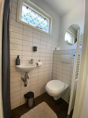 a bathroom with a toilet and a sink and a window at La Luna - Desi in Heerhugowaard