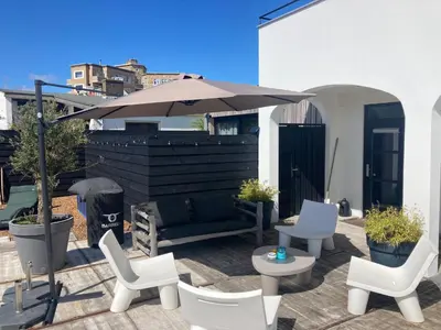 a patio with white chairs and an umbrella at Villa Zandvoort in Zandvoort