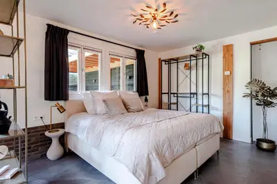 a bedroom with a large bed and a chandelier at Bed and Beach Zandvoort in Zandvoort